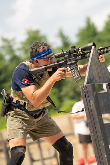 Jake shooting a rifle from a barricade